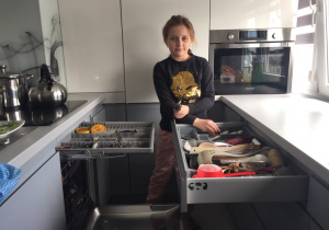 dziewczynka wyjmuje naczynia ze zmywarki